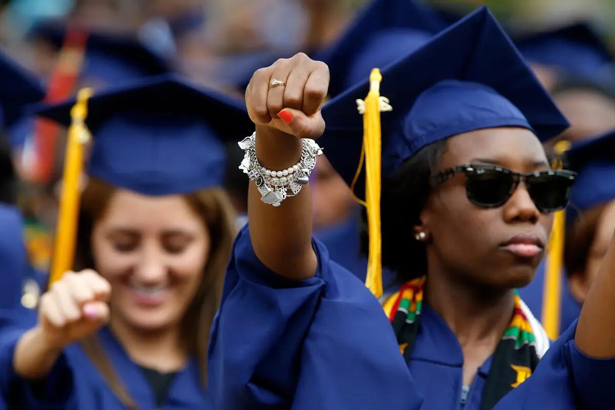 women in cal graduation gowns holding fists in the air